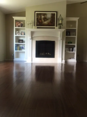 Living room with fireplace flanked by white bookshelves, hardwood floor.
