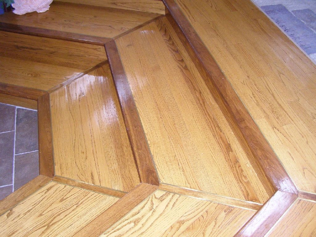 Close-up of a wooden floor with geometric patterns and dark brown borders.