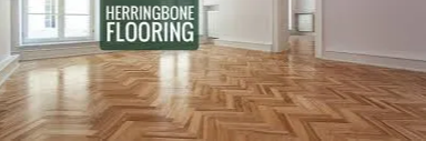 Herringbone wood flooring in a room with a window and white walls.