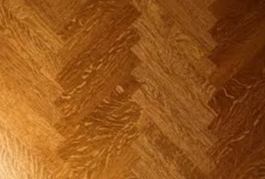 Herringbone pattern wooden floor in warm brown tones.