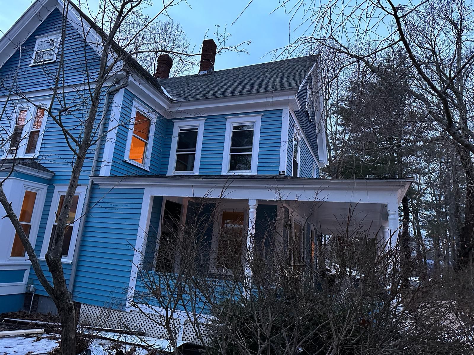 A blue and white house with a porch in the snow.