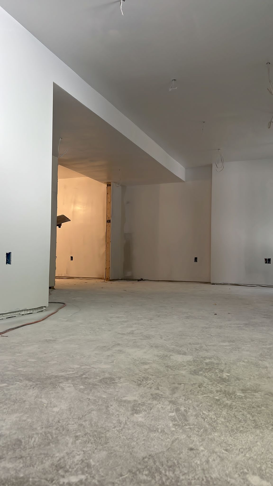 A large empty room with white walls and a concrete floor.