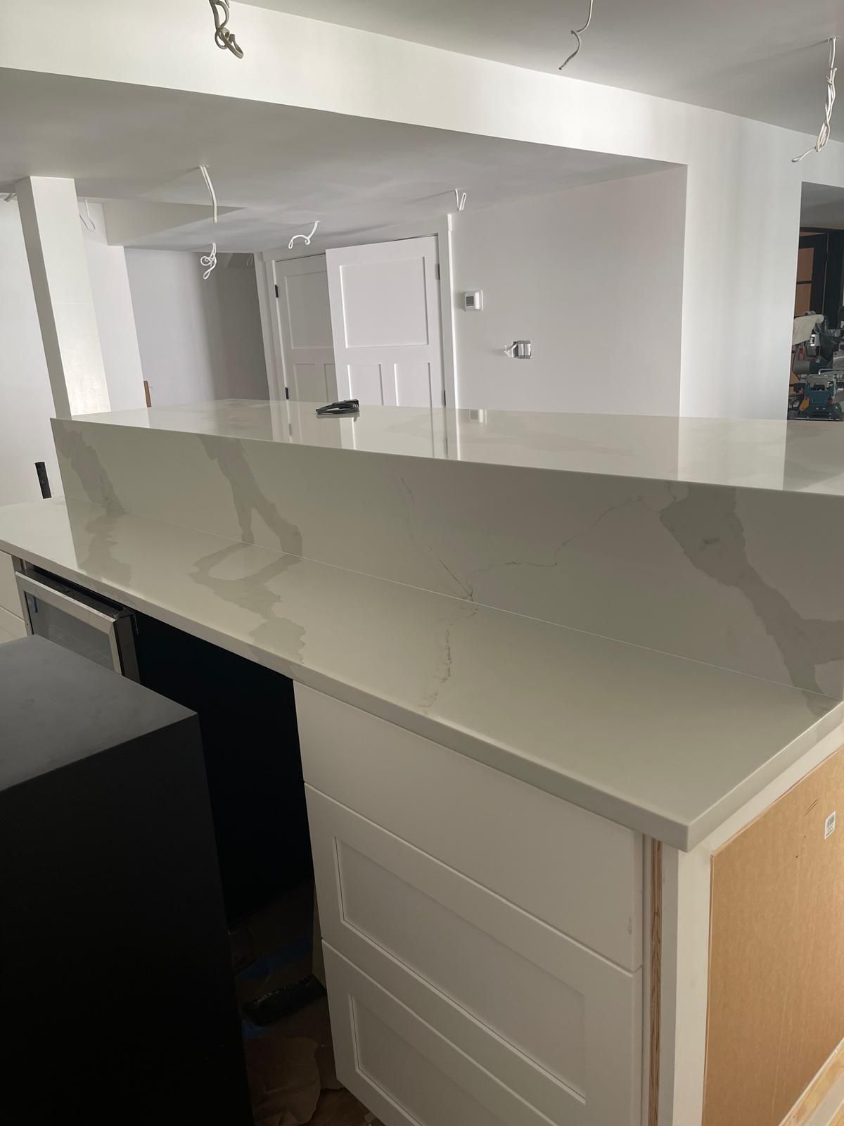 A kitchen with a large white counter top and white cabinets.