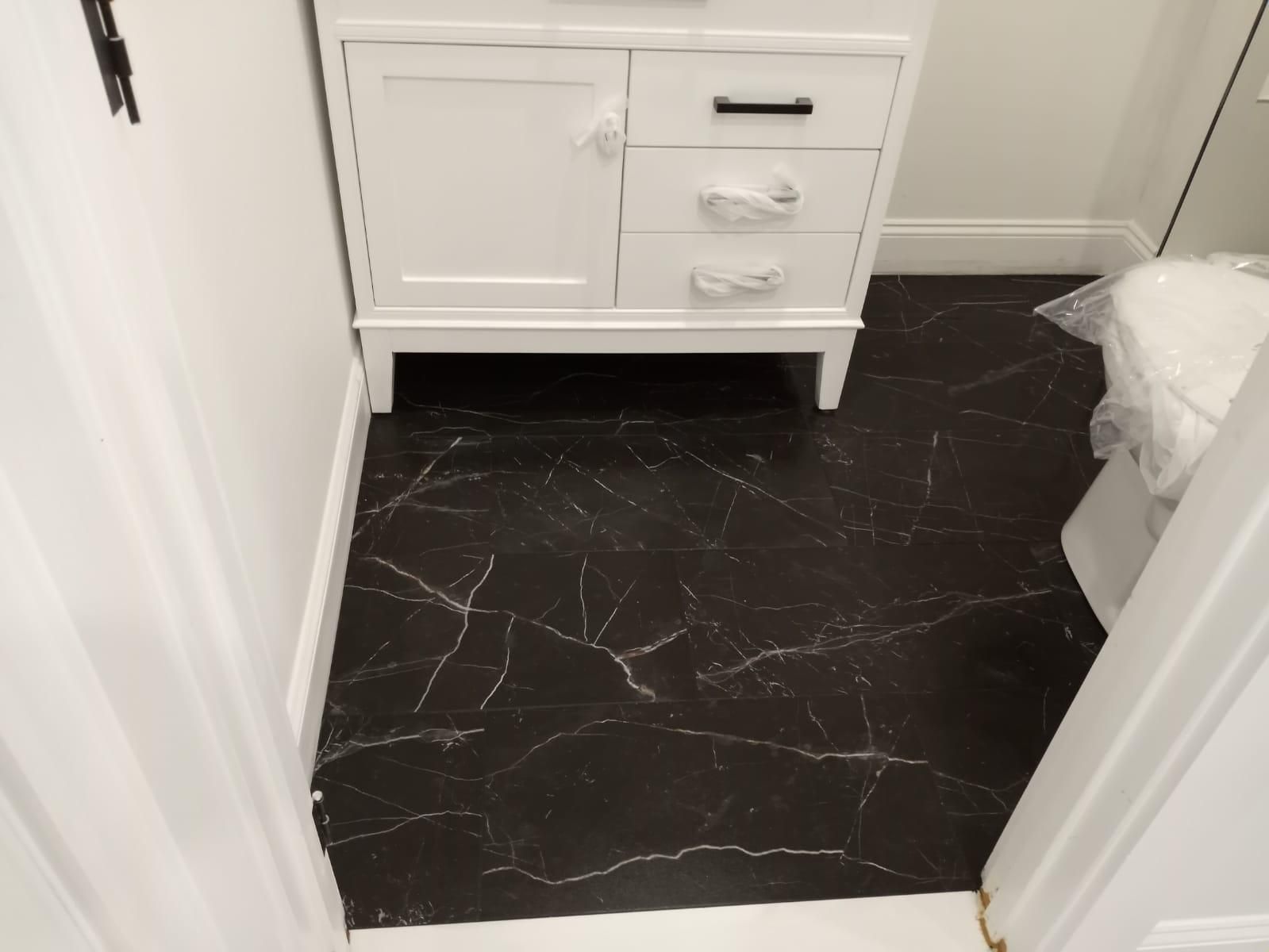 A bathroom with a black marble floor and a white vanity