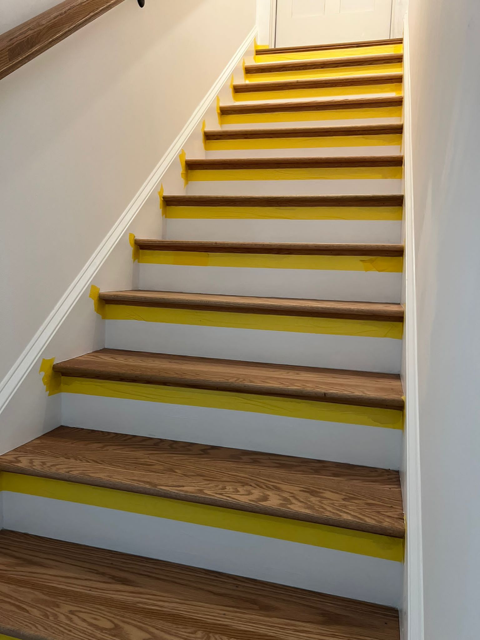 A set of wooden stairs with yellow stripes on the steps.