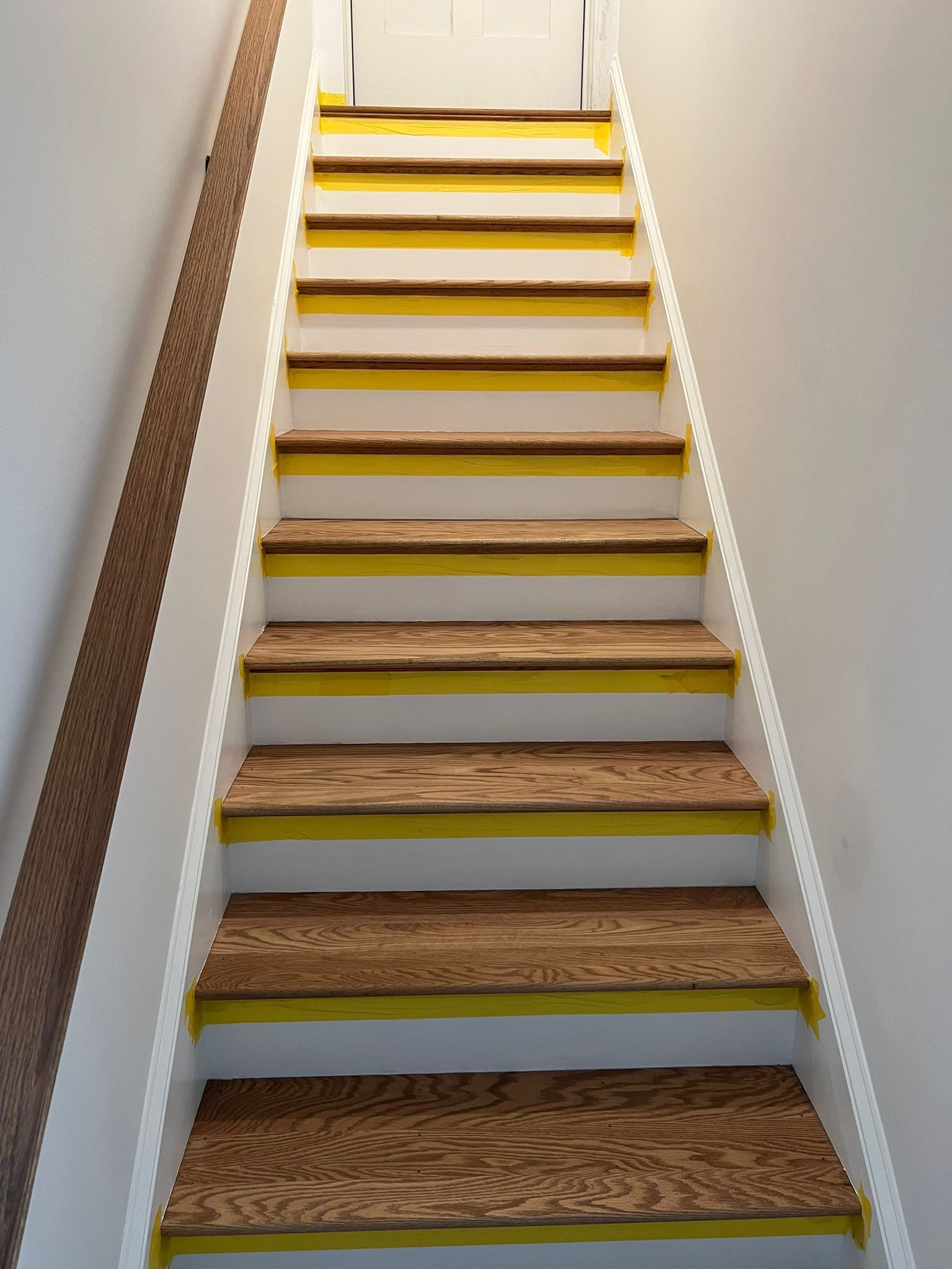 A set of stairs with yellow steps and a white railing.