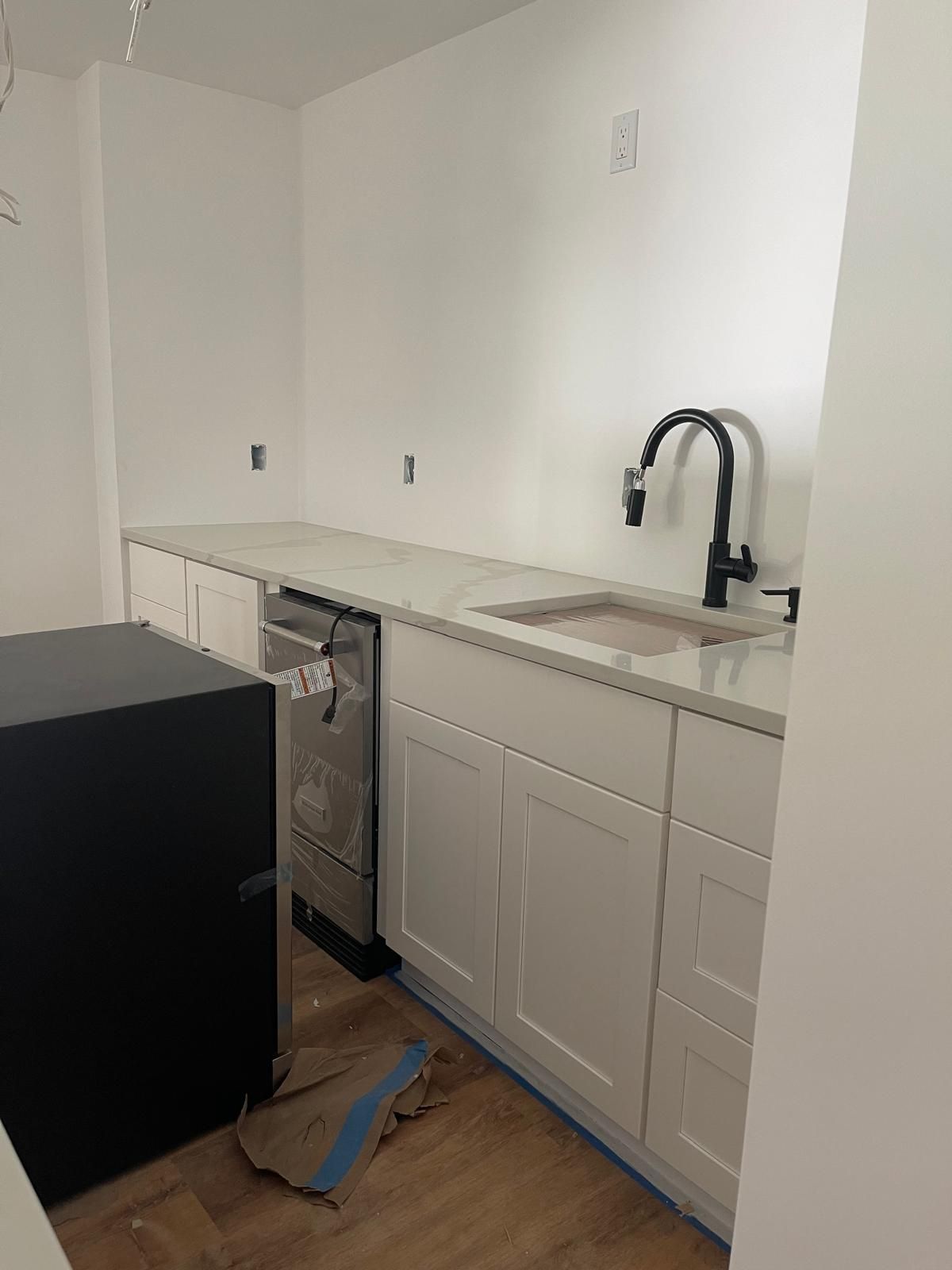 A kitchen with white cabinets, a sink, and a refrigerator.