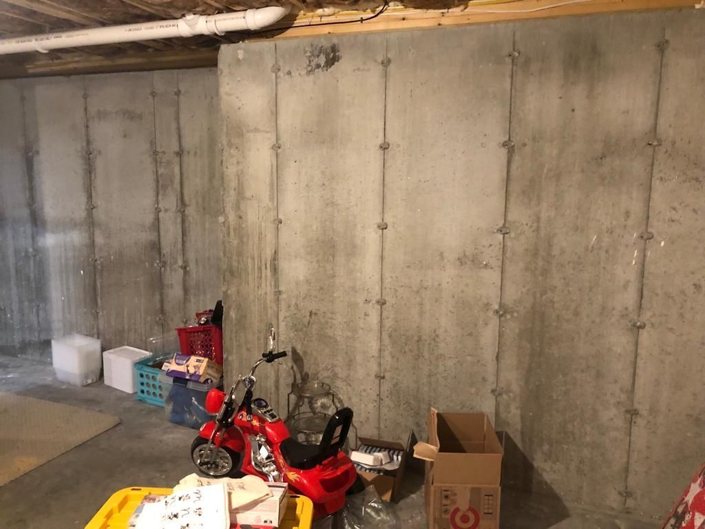 A basement with a concrete wall and a red toy motorcycle.