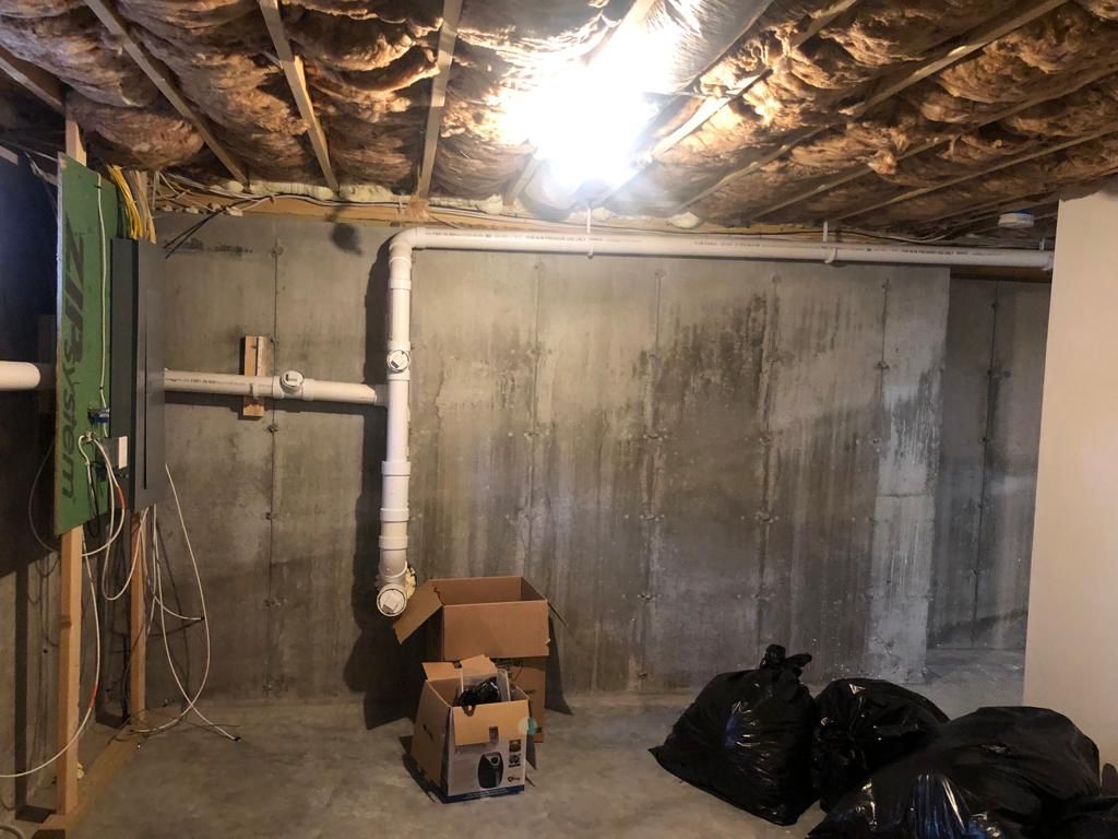 A basement with a concrete wall and a box on the floor.