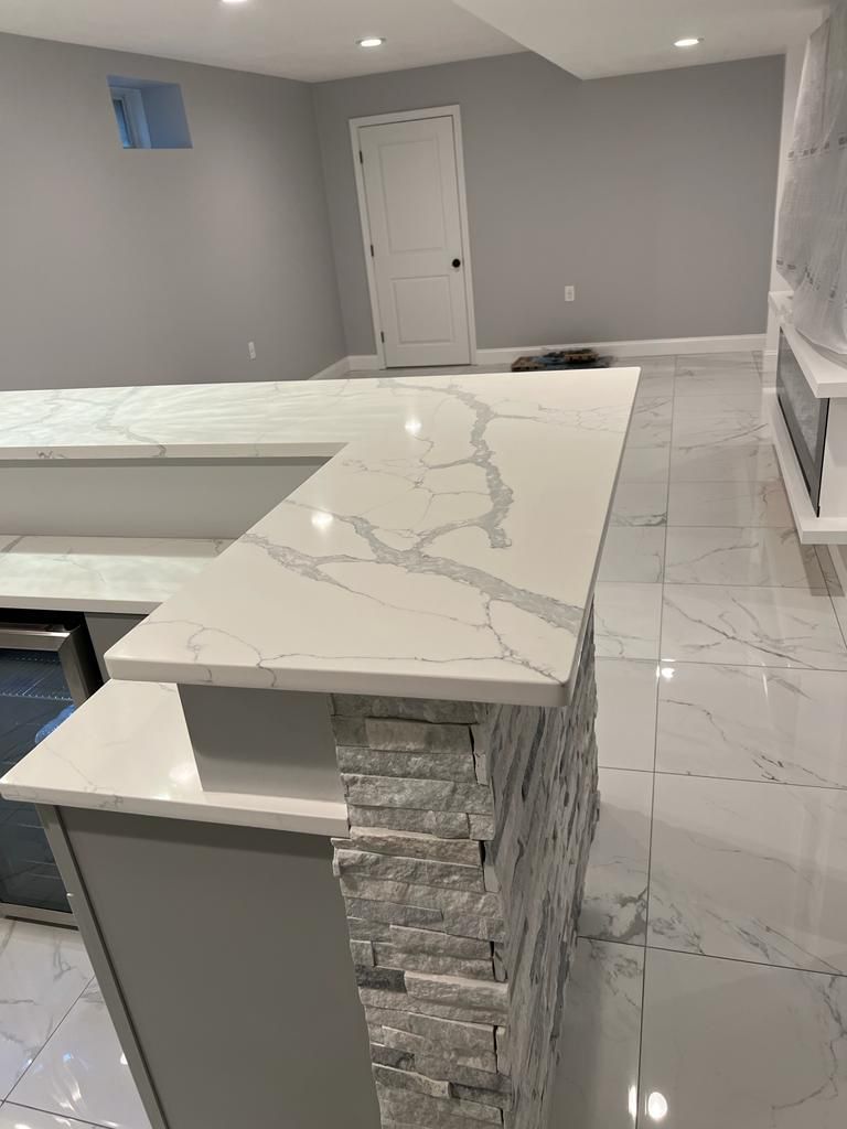 A kitchen with a marble countertop and a brick wall.