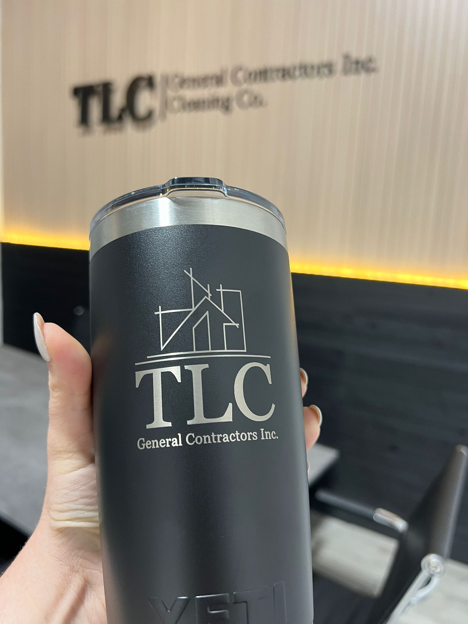 A person is holding a black tumbler.