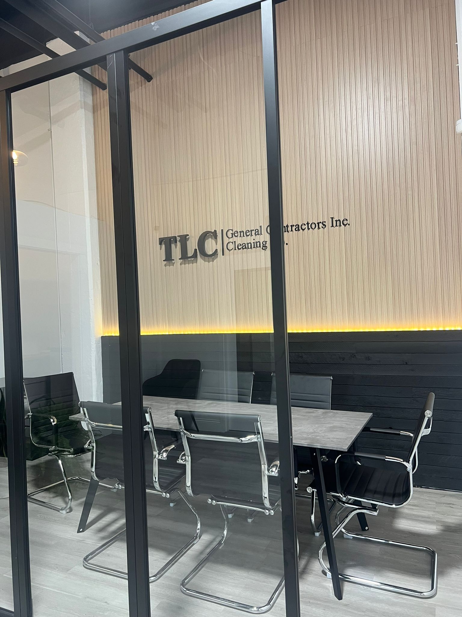 A conference room with a table and chairs behind a glass wall.