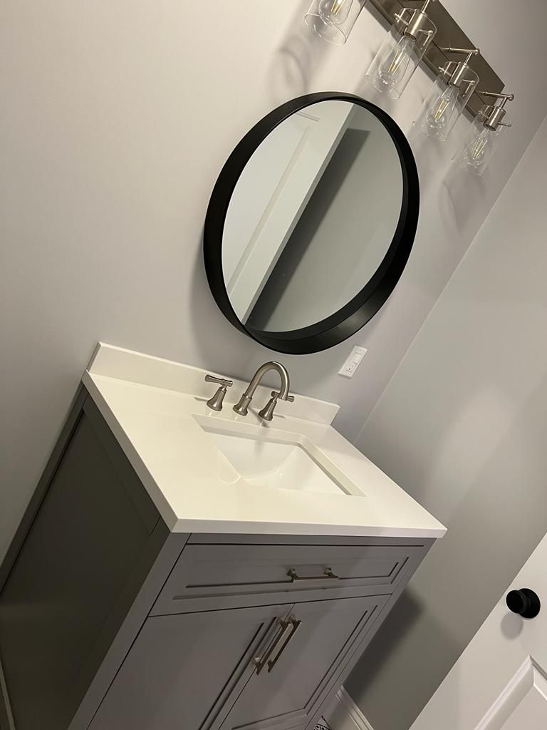 A bathroom sink with a round mirror above it.