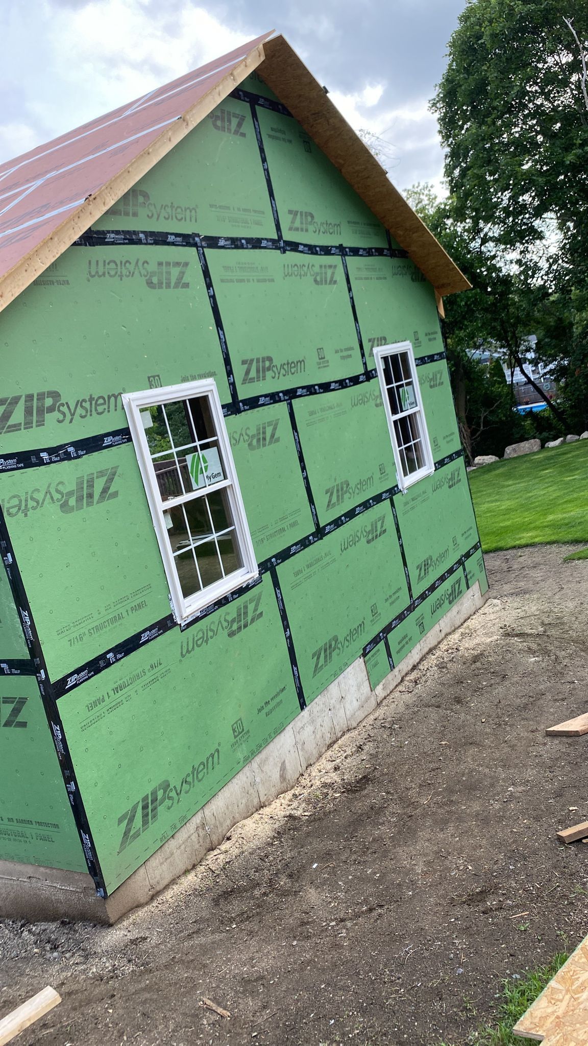 A house is being built with green siding and white windows.