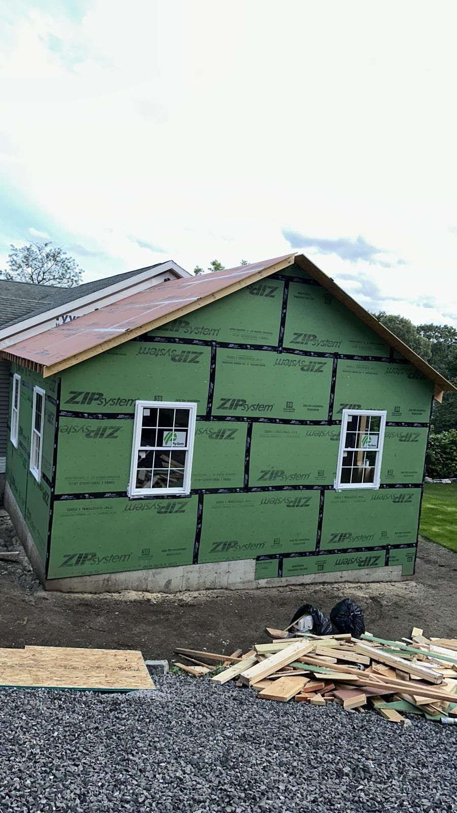 A house is being built with green siding and a red roof.