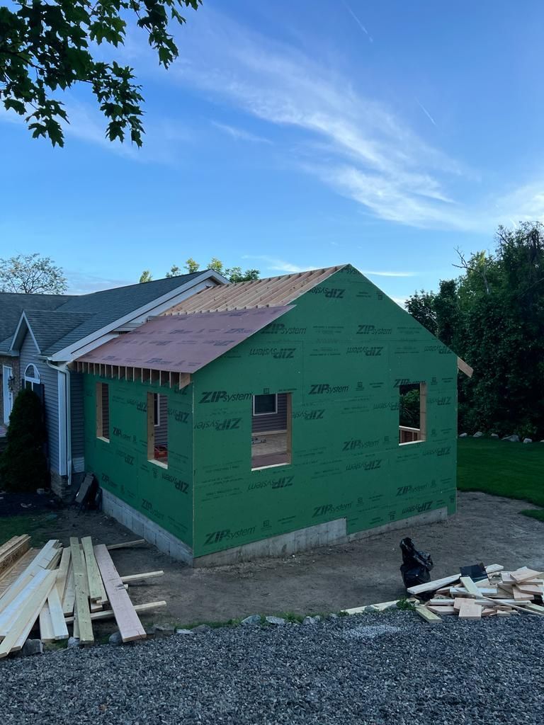 A house is being built with green siding and a pink roof.