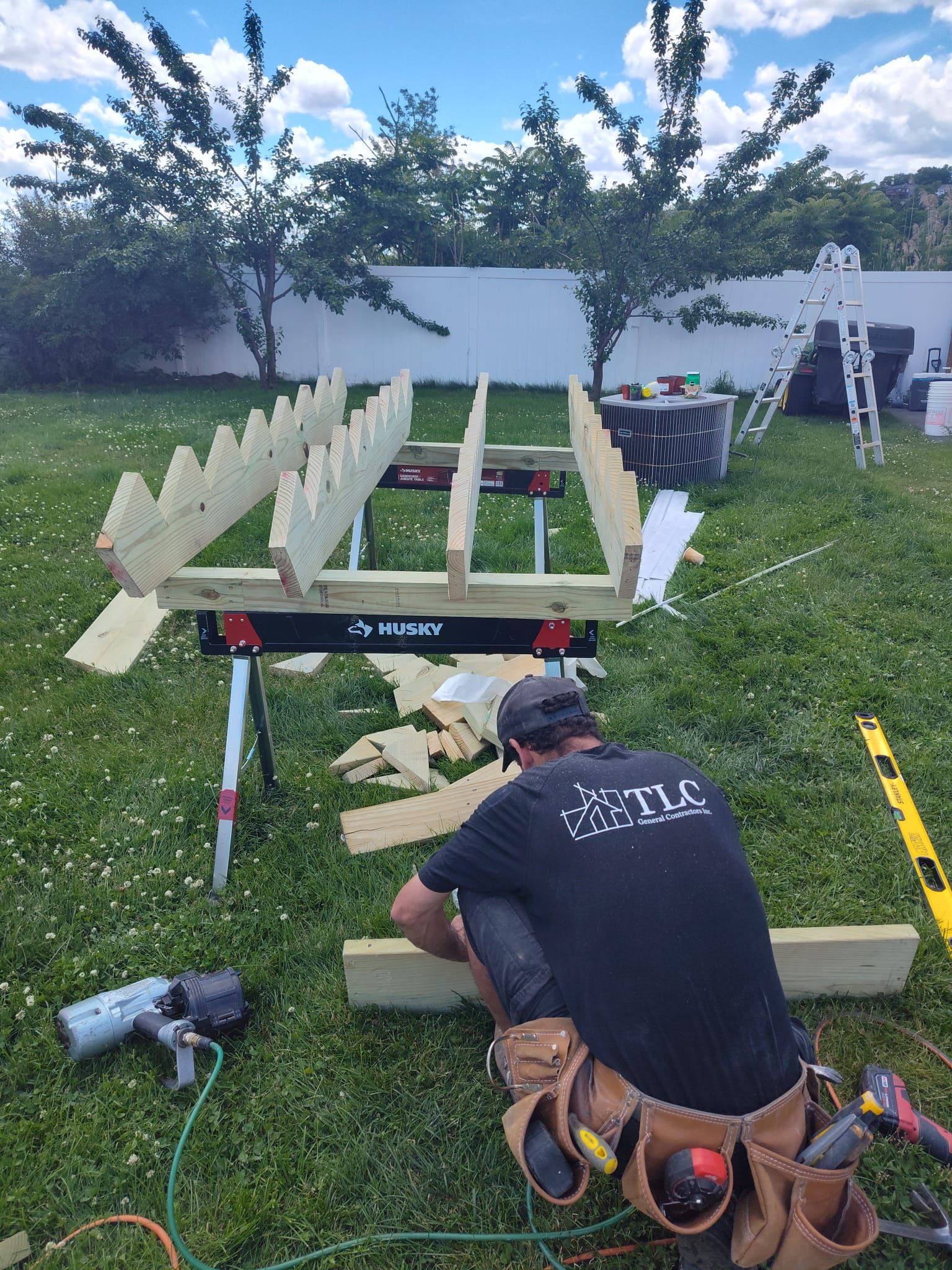 A man is working on a wooden structure in a backyard.