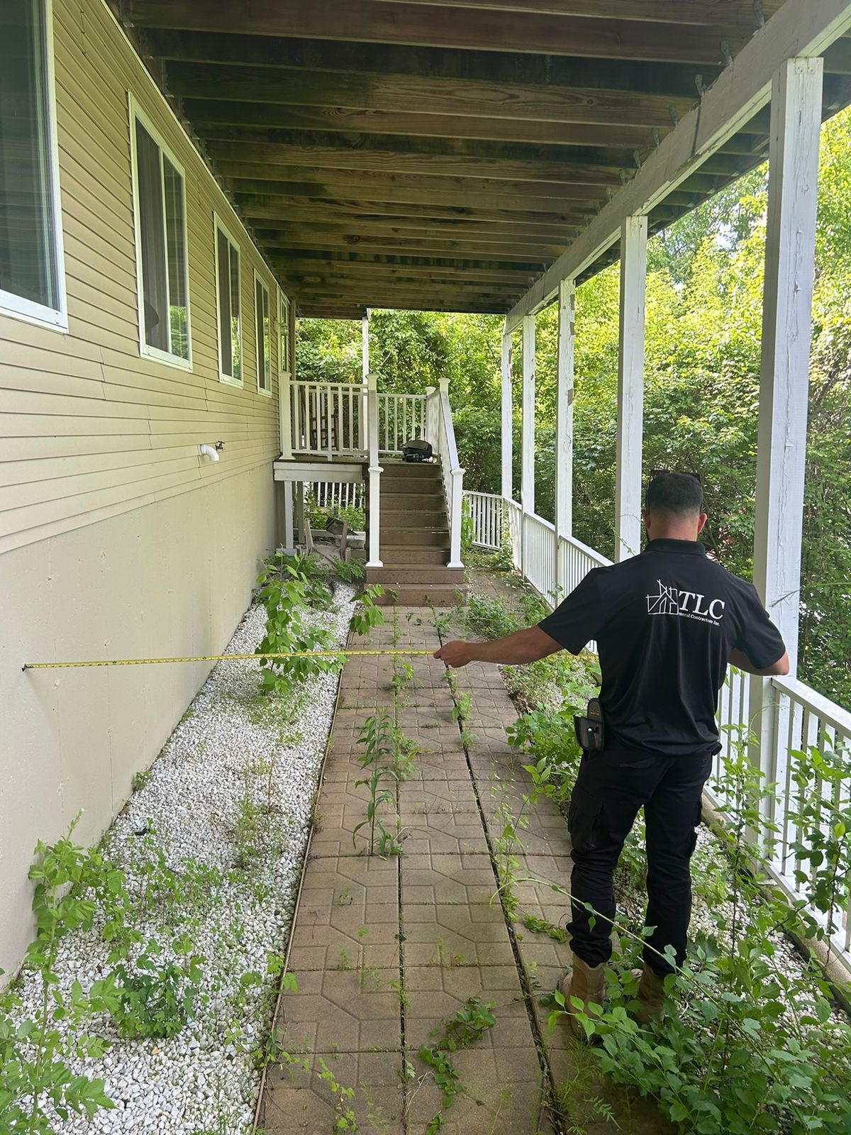 A man is standing on a porch next to a house.