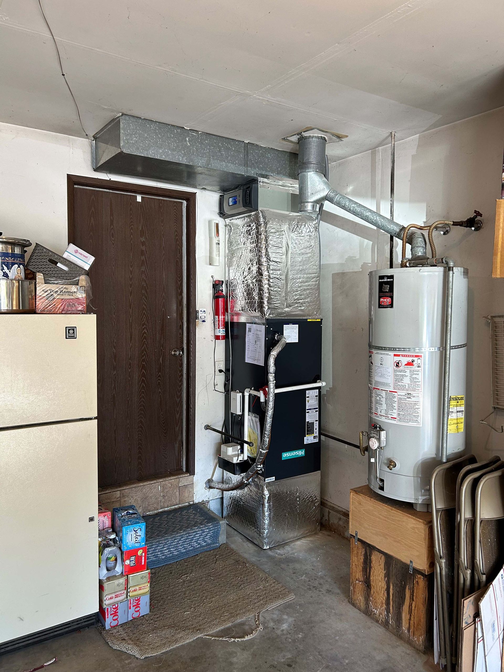 A room with a refrigerator and a water heater in it.