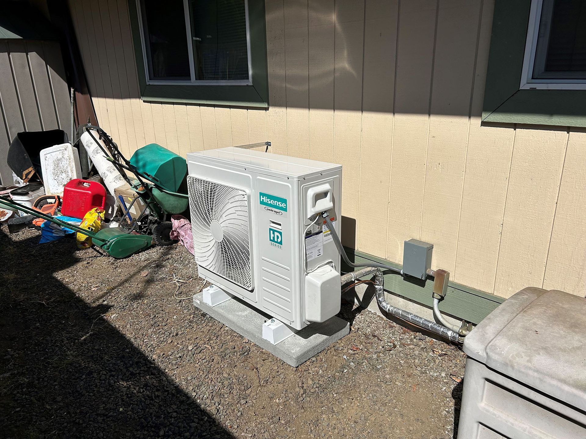 A white air conditioner is sitting on the side of a house.