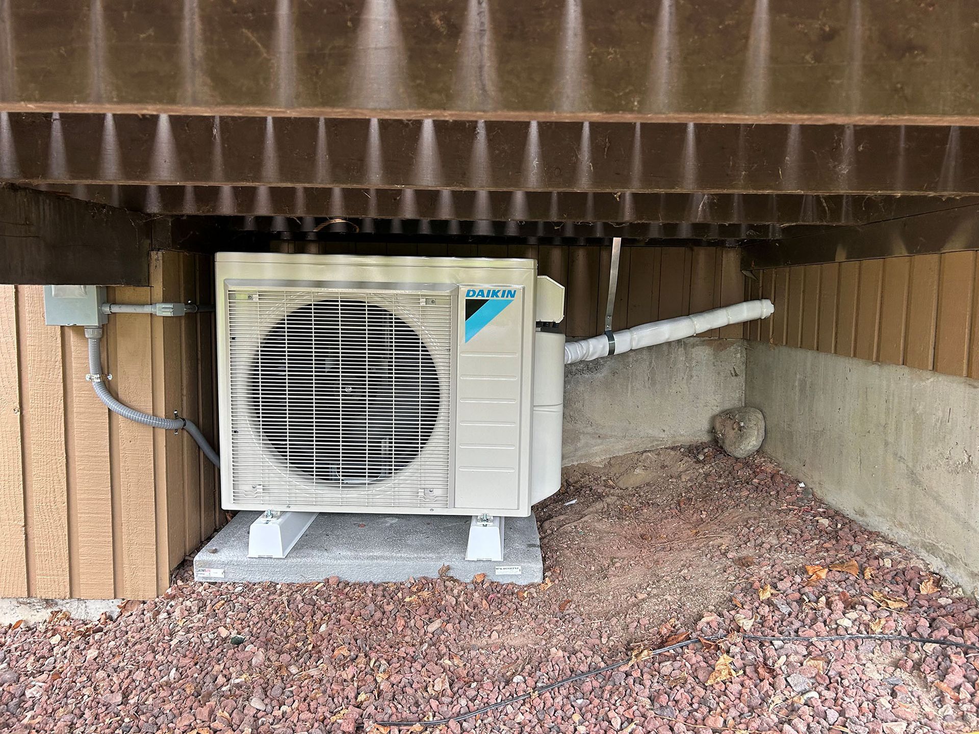 A large air conditioner is sitting under a building.