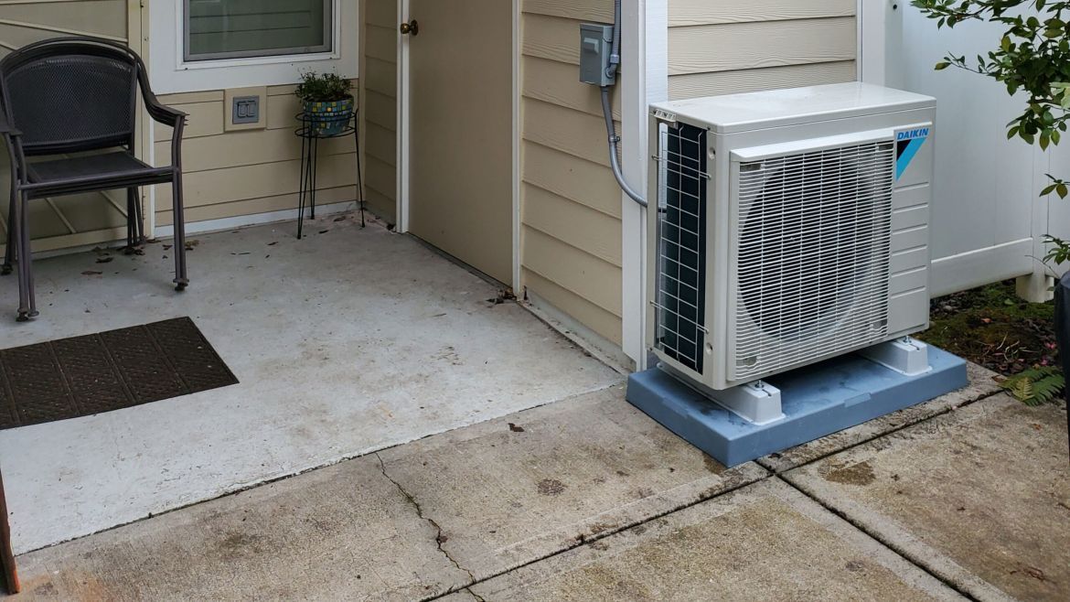A large air conditioner is sitting on the side of a house.