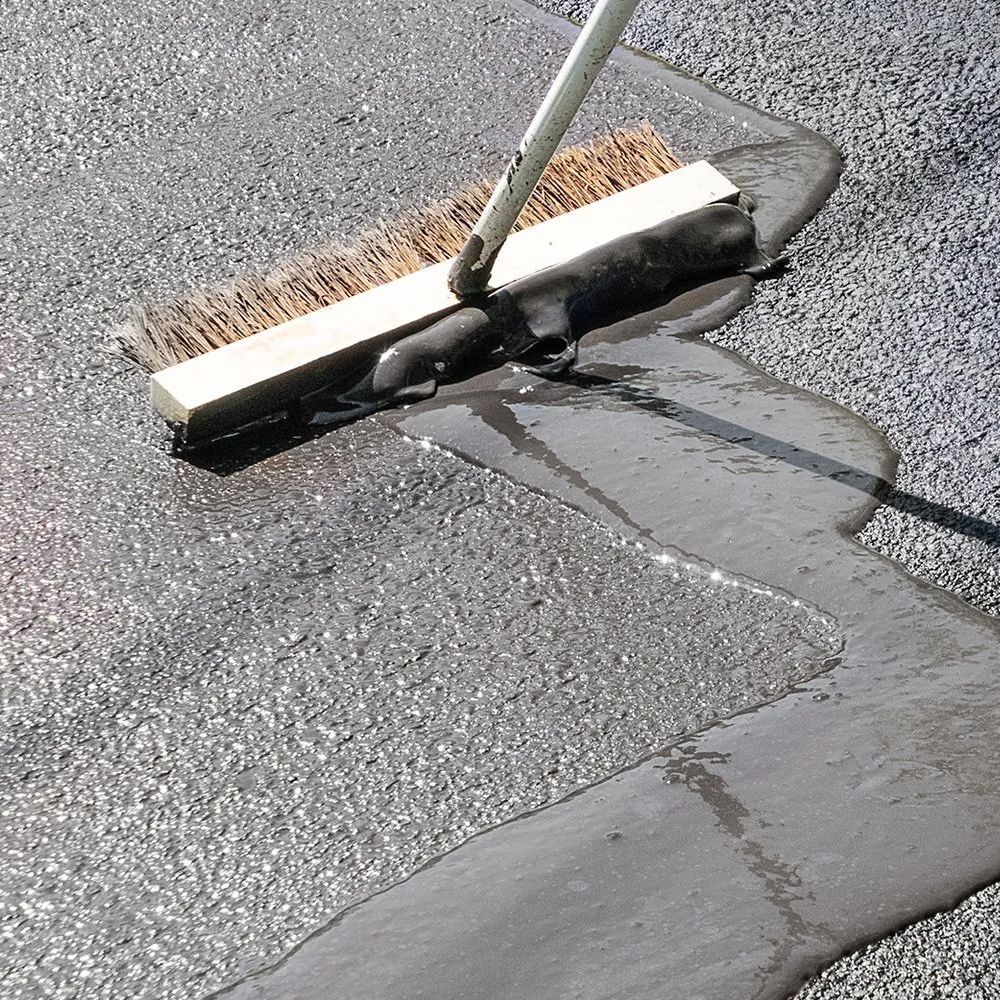 A broom is being used to spread asphalt on the ground