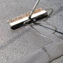 A broom is being used to spread asphalt on the ground