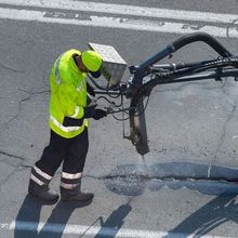 A man in a yellow jacket is working on a road