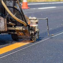 A machine is painting a yellow line on the road.