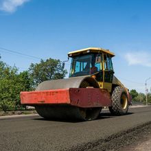 A red and yellow roller is driving down a road.