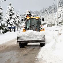 A snow plow is driving down a snow covered road