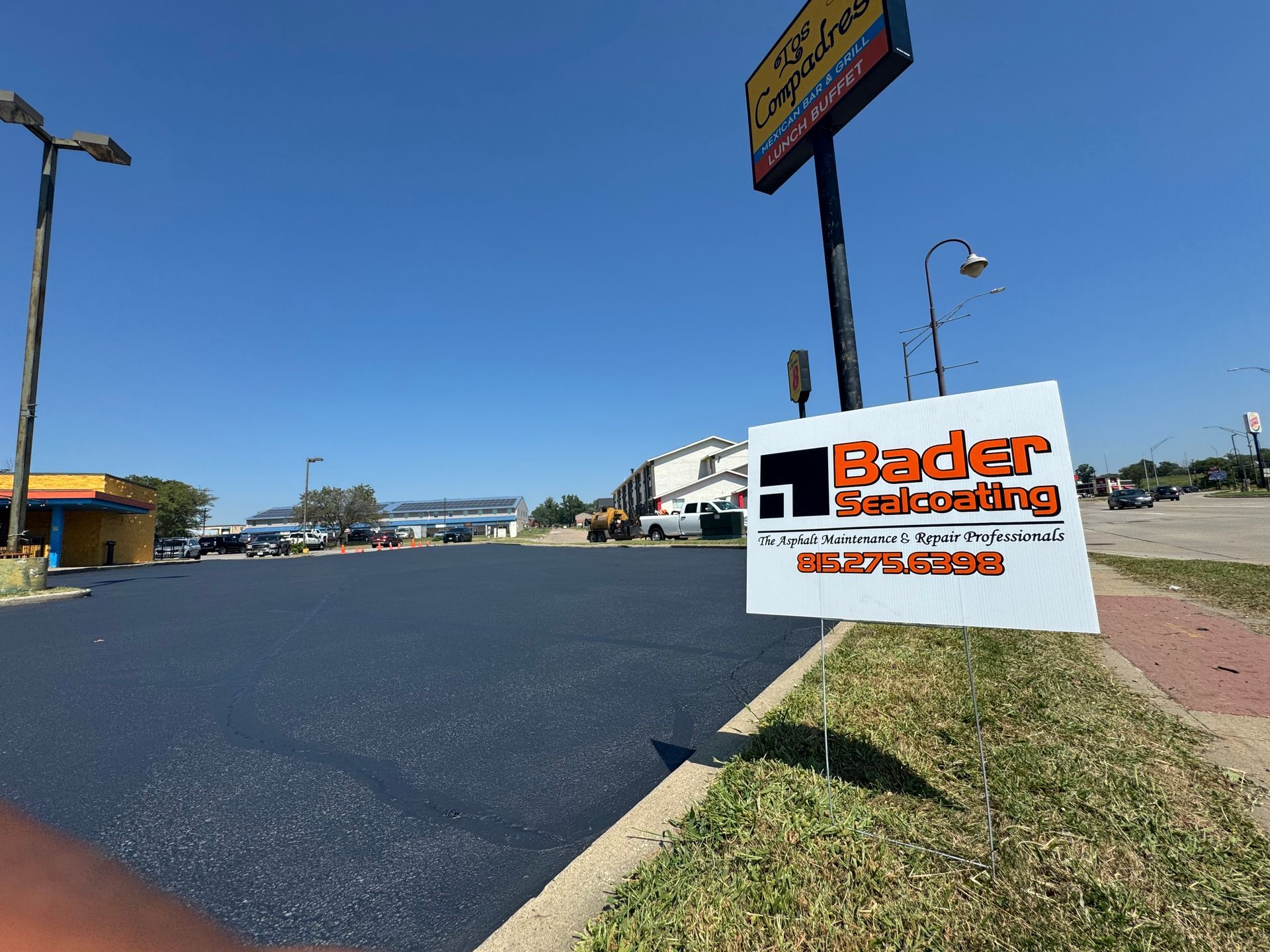 A sign for bader paving is sitting on the side of the road.