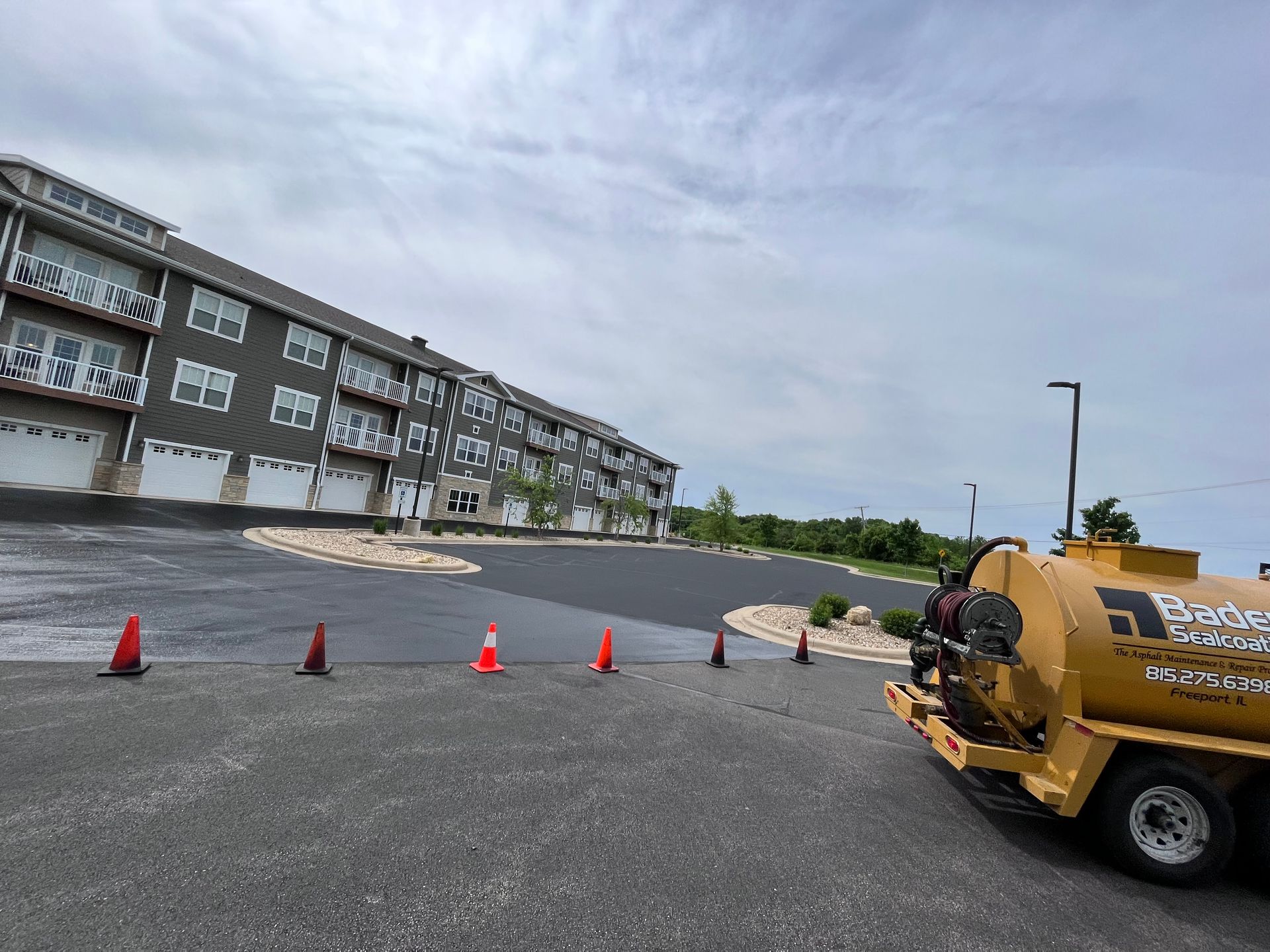 A yellow truck is parked in a parking lot in front of a building.