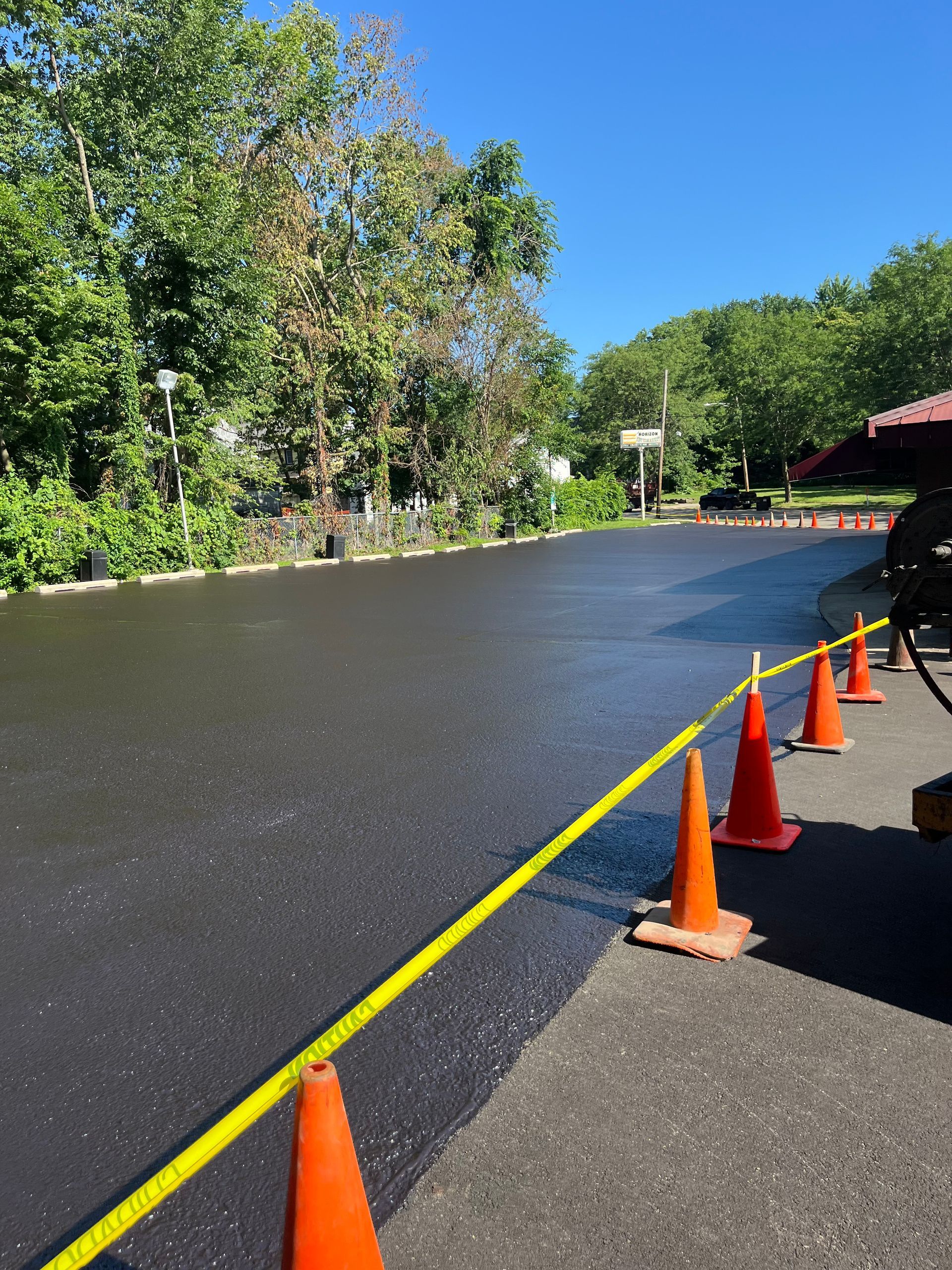 A row of orange traffic cones are lined up on the side of a road