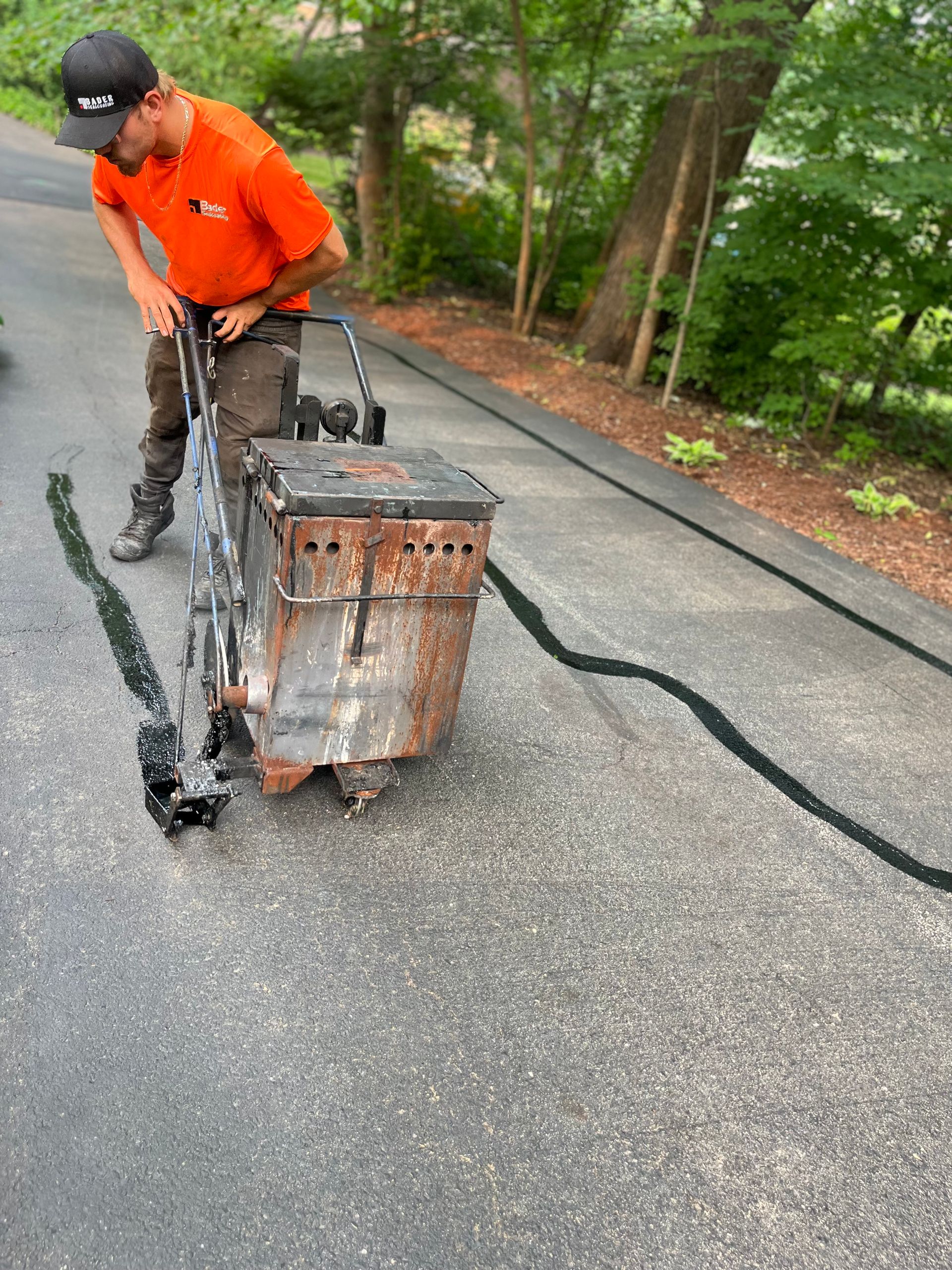 A man is using a machine to spread asphalt on a road