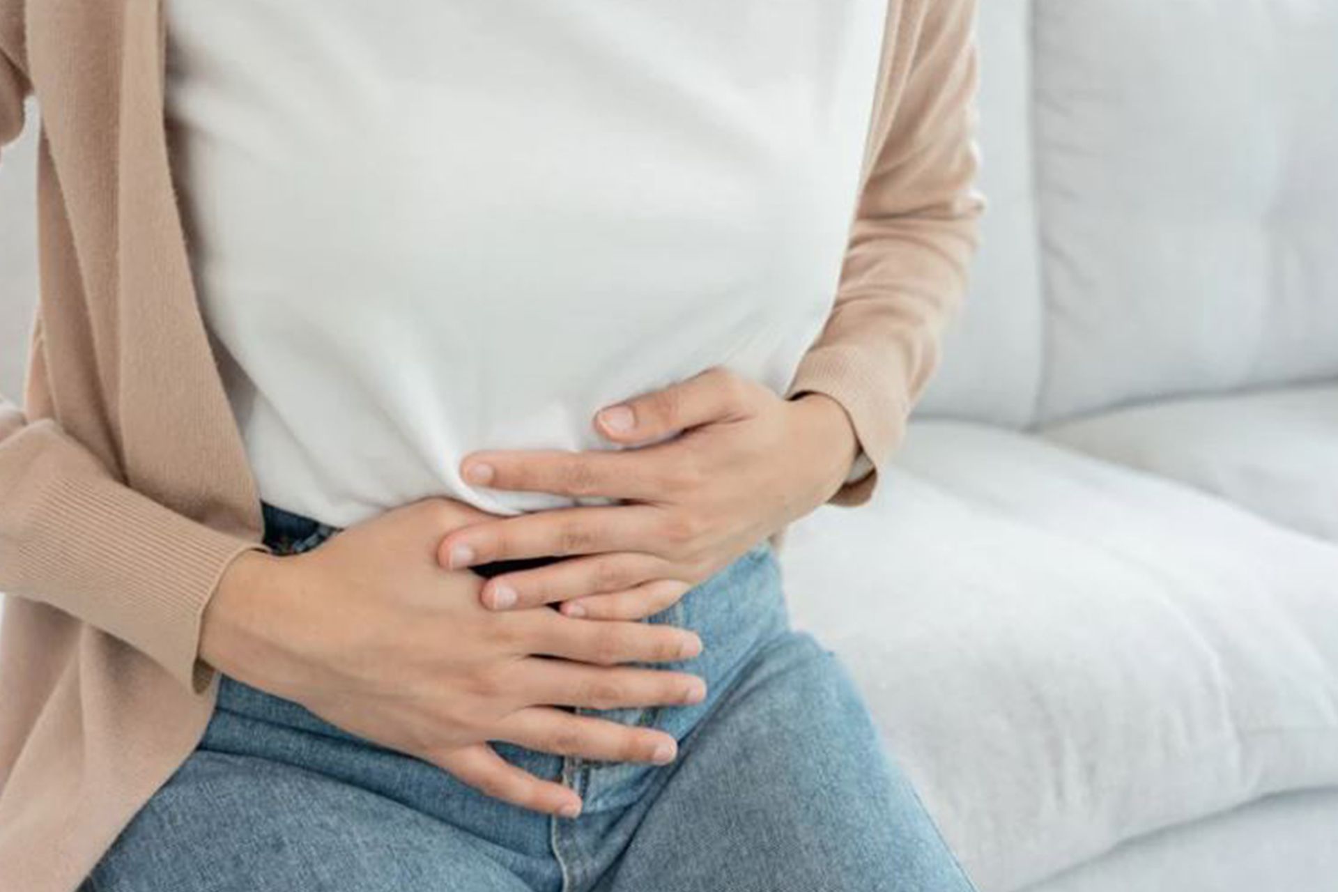 A woman is sitting on a couch holding her stomach.