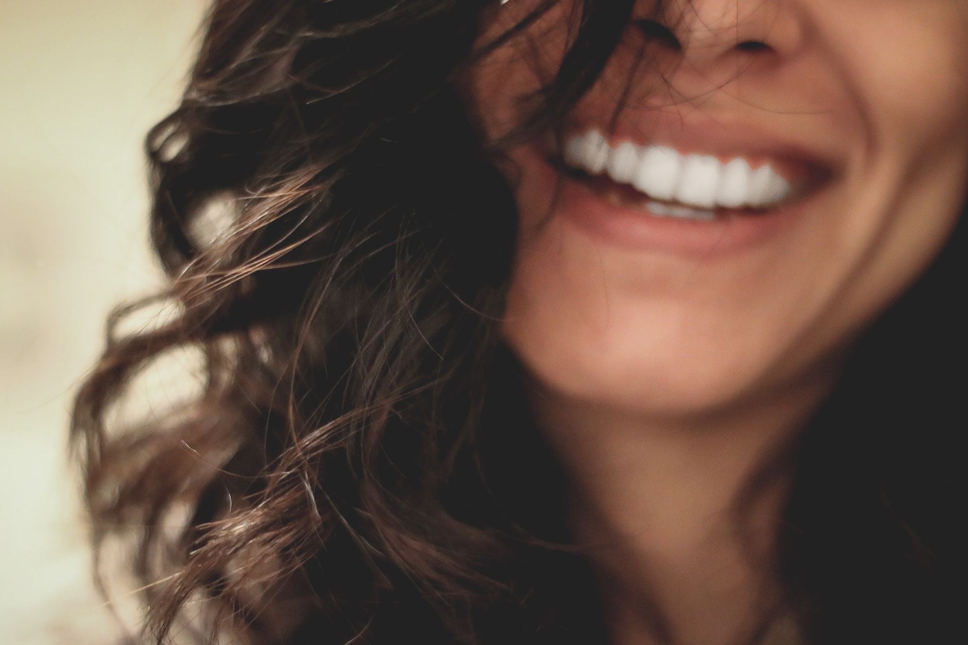 A close up of a woman's face smiling with her hair blowing in the wind.