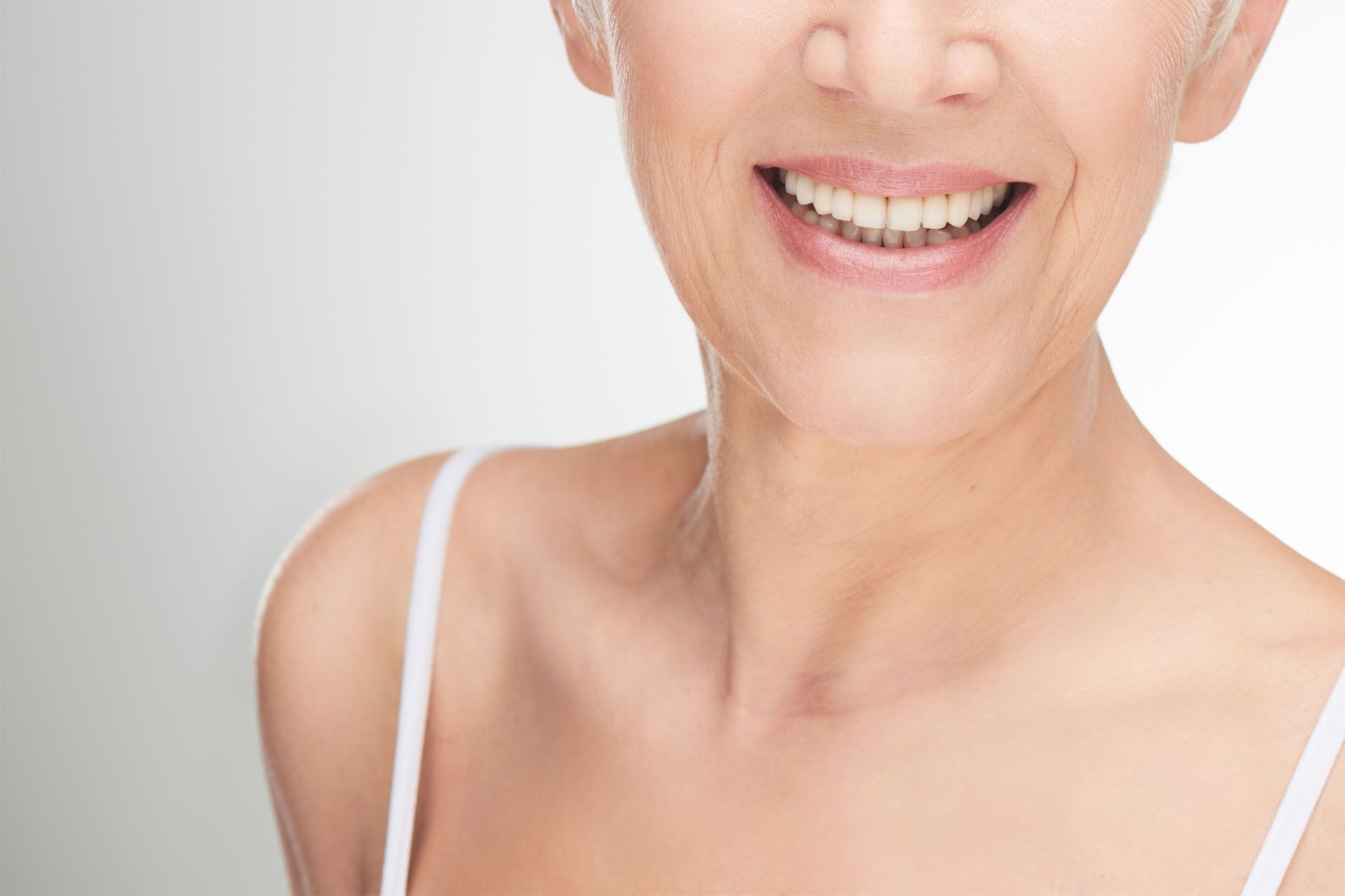 A close up of a woman's neck and face smiling.