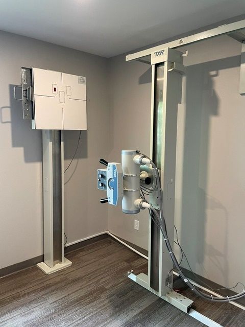 An x-ray machine is sitting in a room with a wooden floor