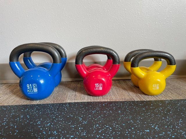 Three different colored kettlebells are lined up on a counter