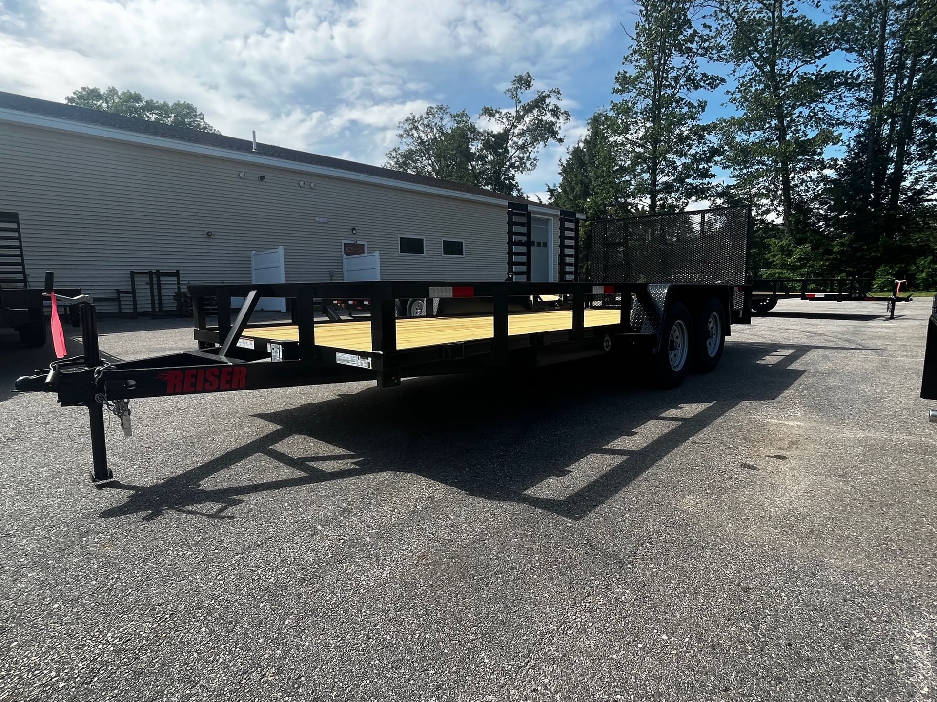 A trailer is parked in a gravel lot with a building in the background