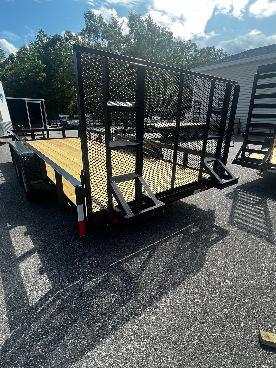 A trailer with a wooden deck and stairs is parked on the side of the road.