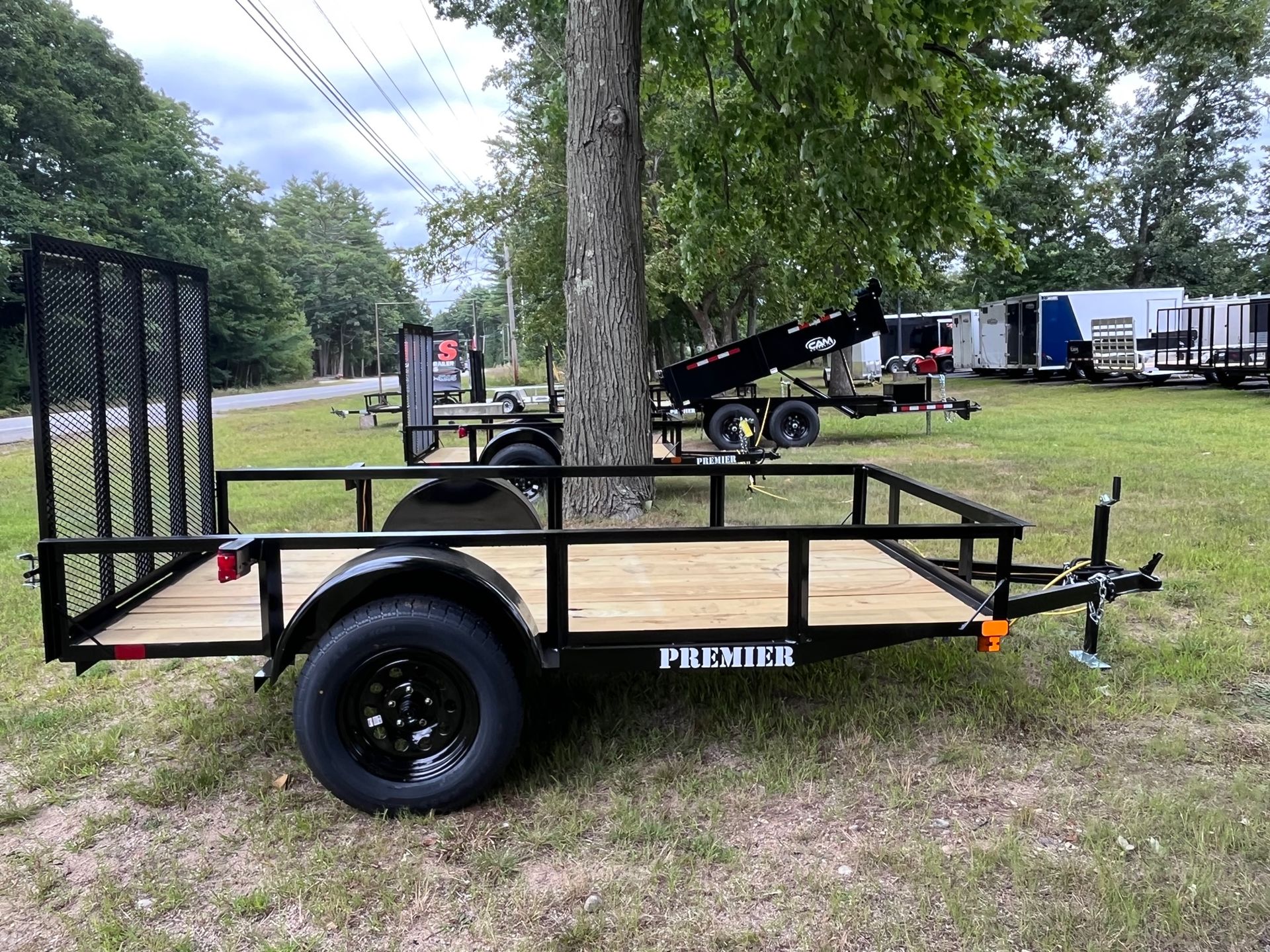 A trailer is parked in a grassy field next to a tree.