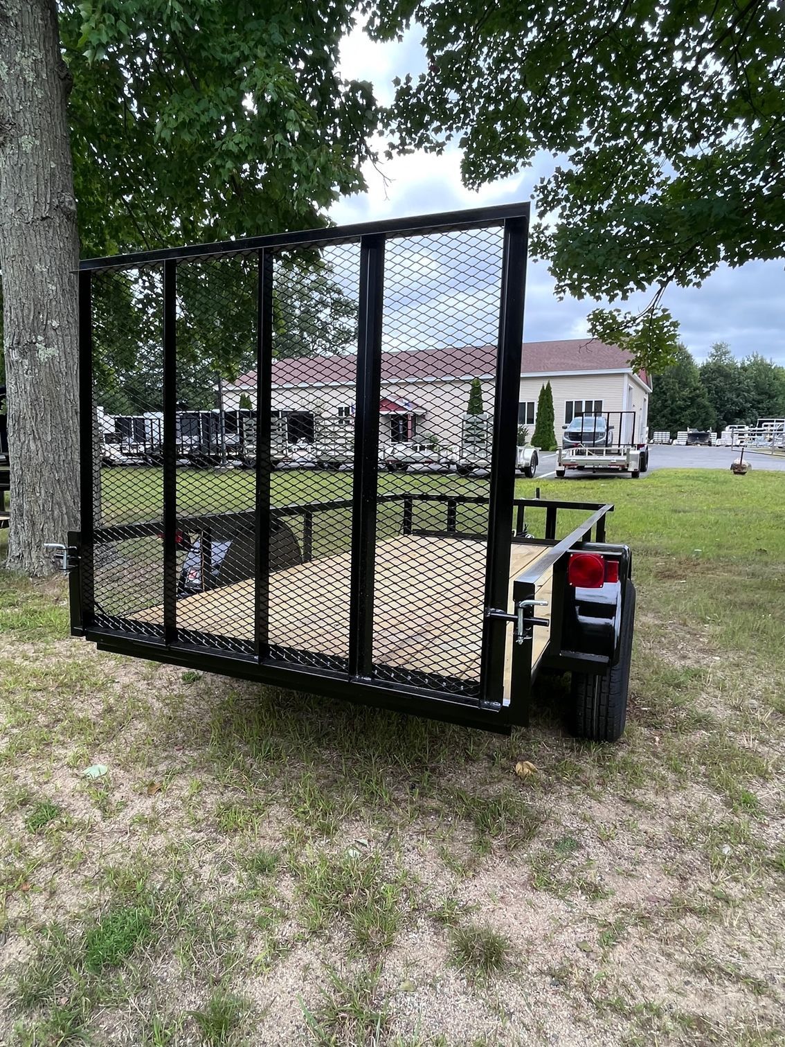 A trailer is parked in a grassy field next to a tree.