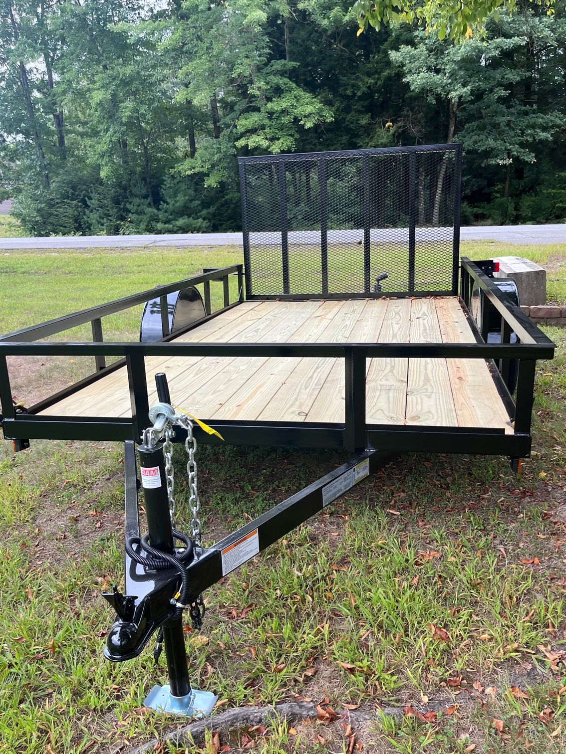 A trailer is sitting on top of a lush green field.