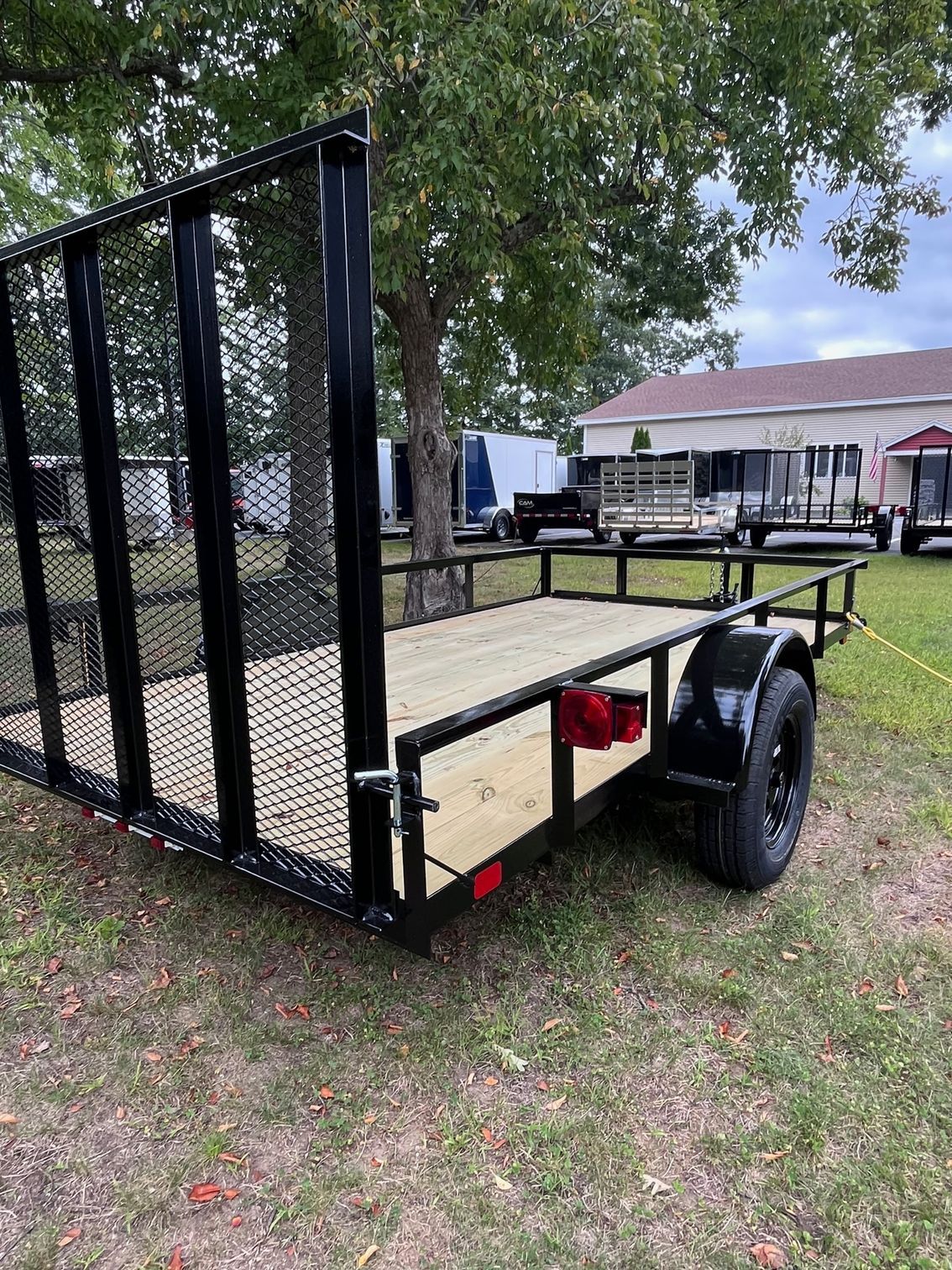 A trailer is parked in a grassy field next to a tree.