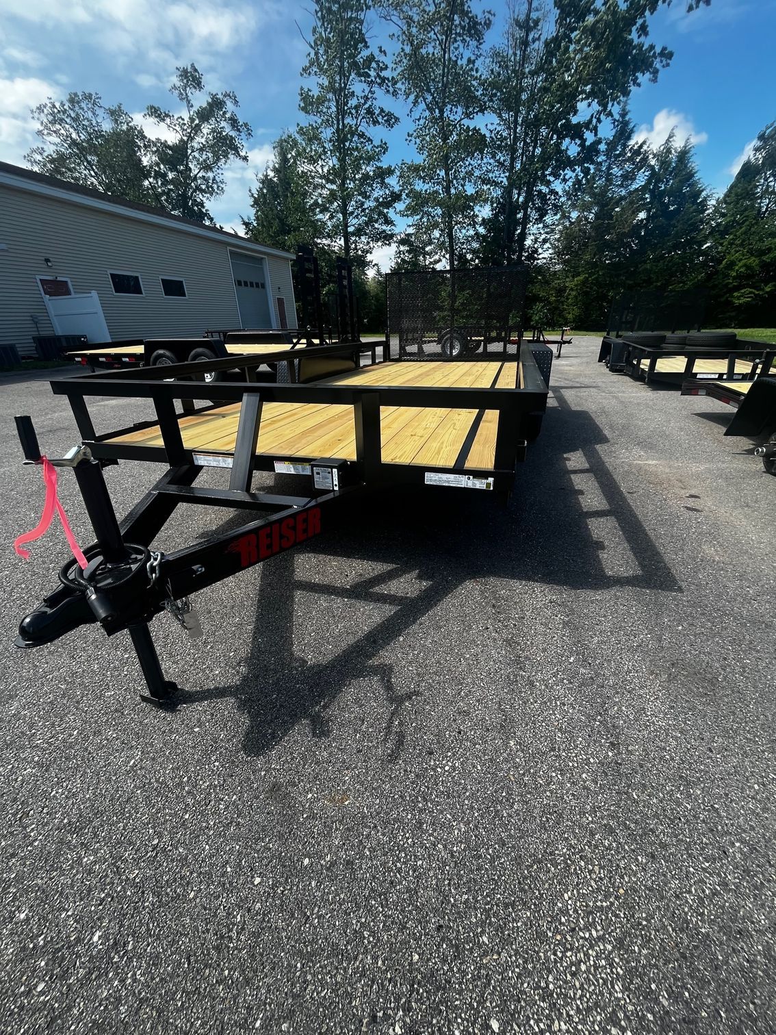 A trailer with a wooden deck is parked on the side of the road.