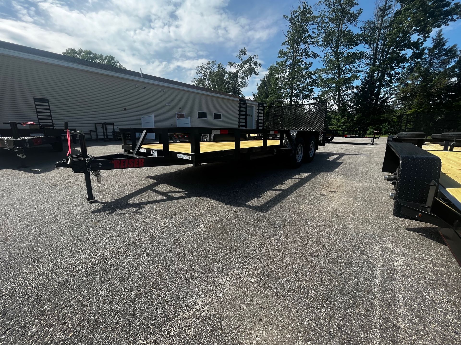 A trailer is parked in a gravel lot in front of a building.