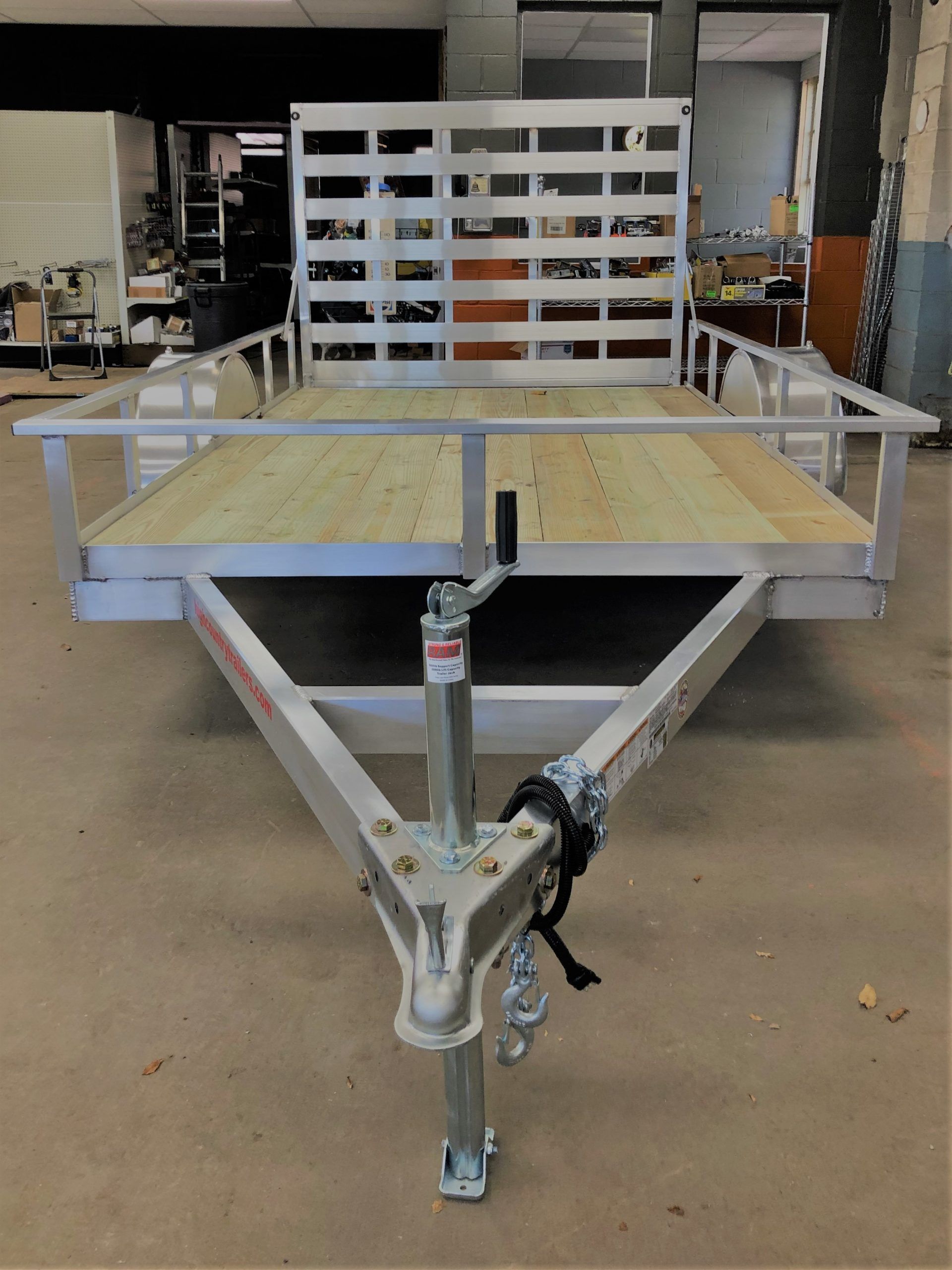A trailer with a wooden deck is parked in a garage.